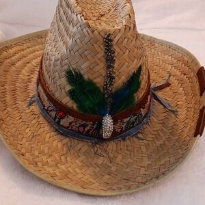 Straw hat with feathers, leather, jean fabric, ribbon, and bejeweled charm.